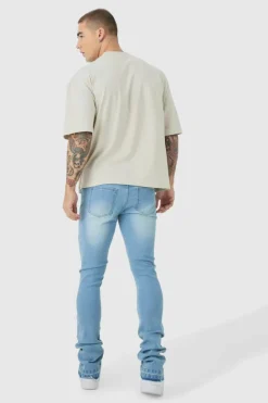 Shop boohooMAN Skinny Stacked Flared Jeans With Knee Rip light blue