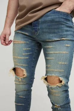 Shop boohooMAN Tall Extreme Rip Busted Knee Skinny Jeans mid wash